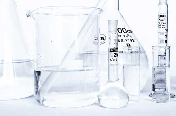 Ampolle, beute e cilindri in laboratorio: simbolo della ricerca e qualità nella produzione di integratori alimentari.